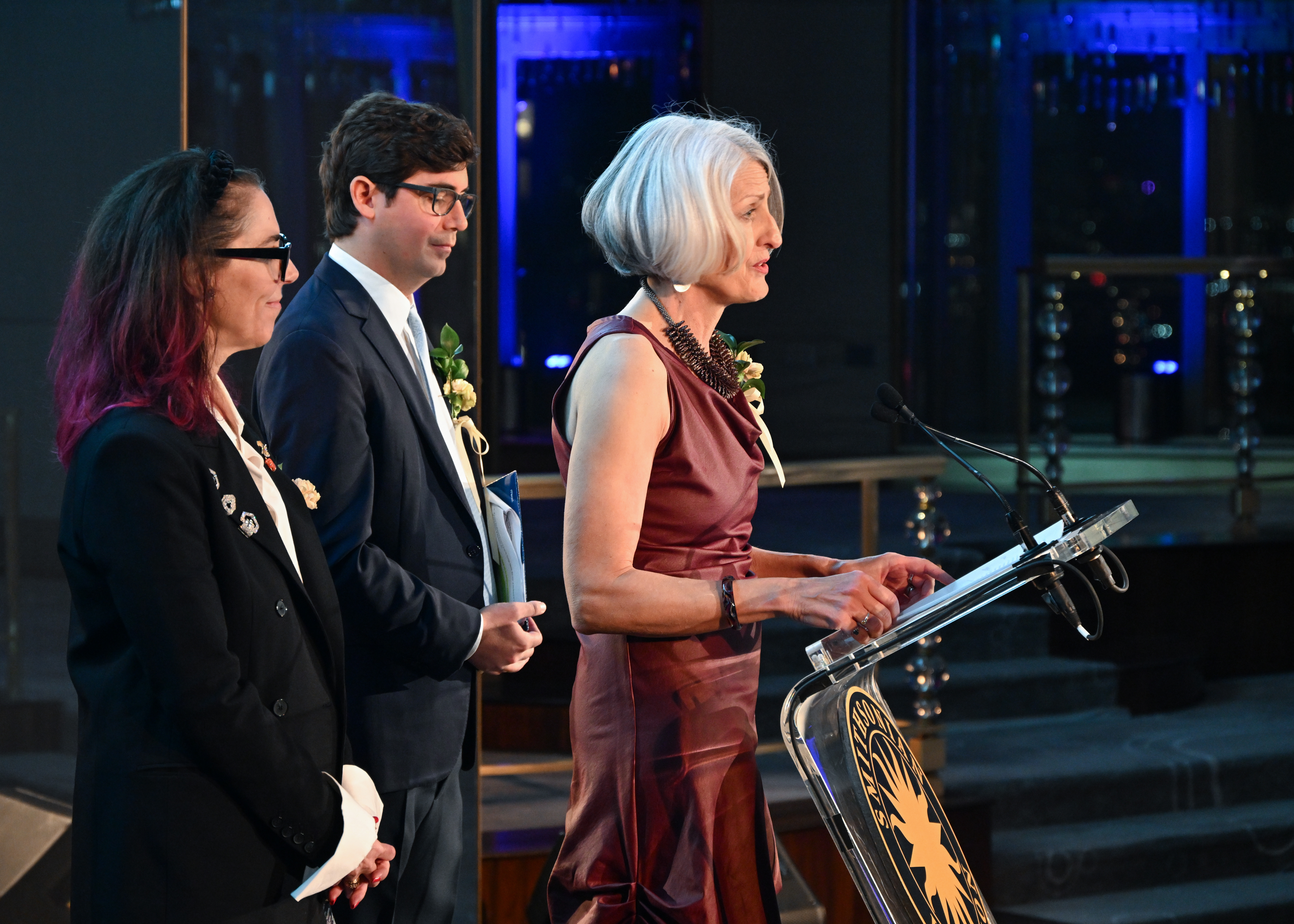 Director Anne Helmreich and gala co-chairs Amanda Quinn Olivar and George Frederick Mead Merck on stage as Anne presents