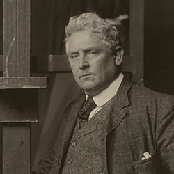 Photo is a portrait of Julian Alden Weir standing against an easel in his studio