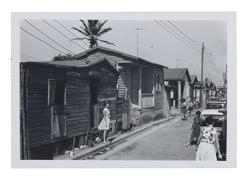 Photograph of a Puerto Rican girl standing on a curb, photographed by Emilio Sanchez.