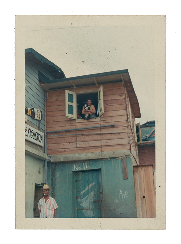 Photo taken by Sanchez in Puerto Rico of a woman leaning out of a window while holding a dog.