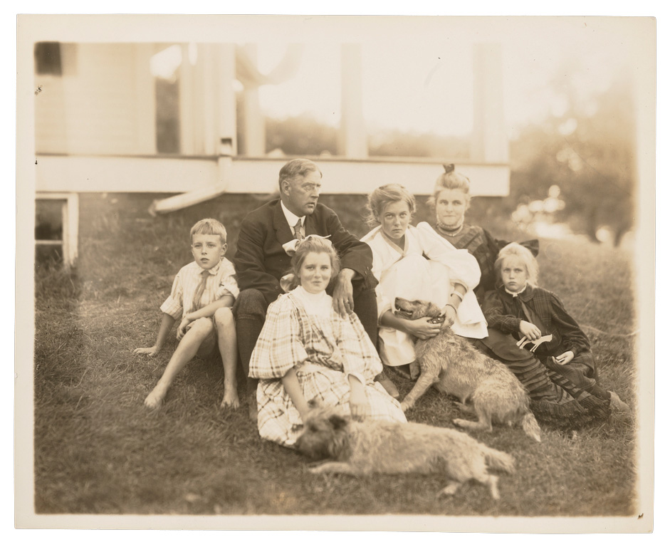 Edmund C. Tarbell and his family photographed in front of their New Hampshire home with their dogs.