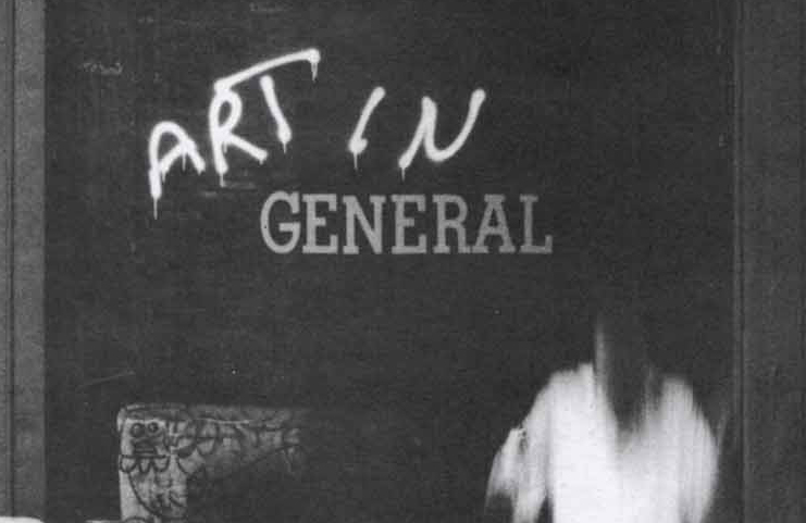 Detail of grayscale photograph of a storefront with blurred figures in the foreground.