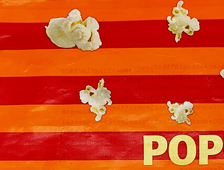 Detail of an orange and bright pink popcorn bag with pictures of popcorn and yellow text that reads pop.