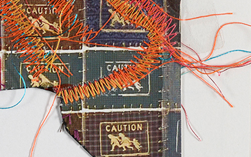 Detail of artwork with wayfinder symbol of family running with the word "caution" with machine stitching in various colors.