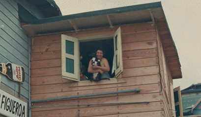 Detail of photograph taken by Emilio Sanchez of a woman holding a dog and leaning out a window in Puerto Rico