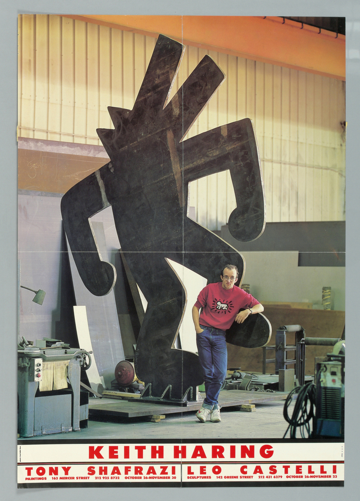 Keith Haring posing with a large black dog sculpture of his design.