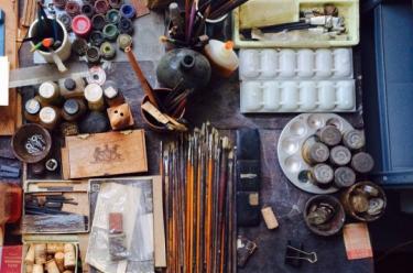 Photograph of an artist's easel side table with paints and other materials